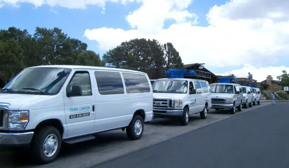 A row of white vans are parked on the side of the road