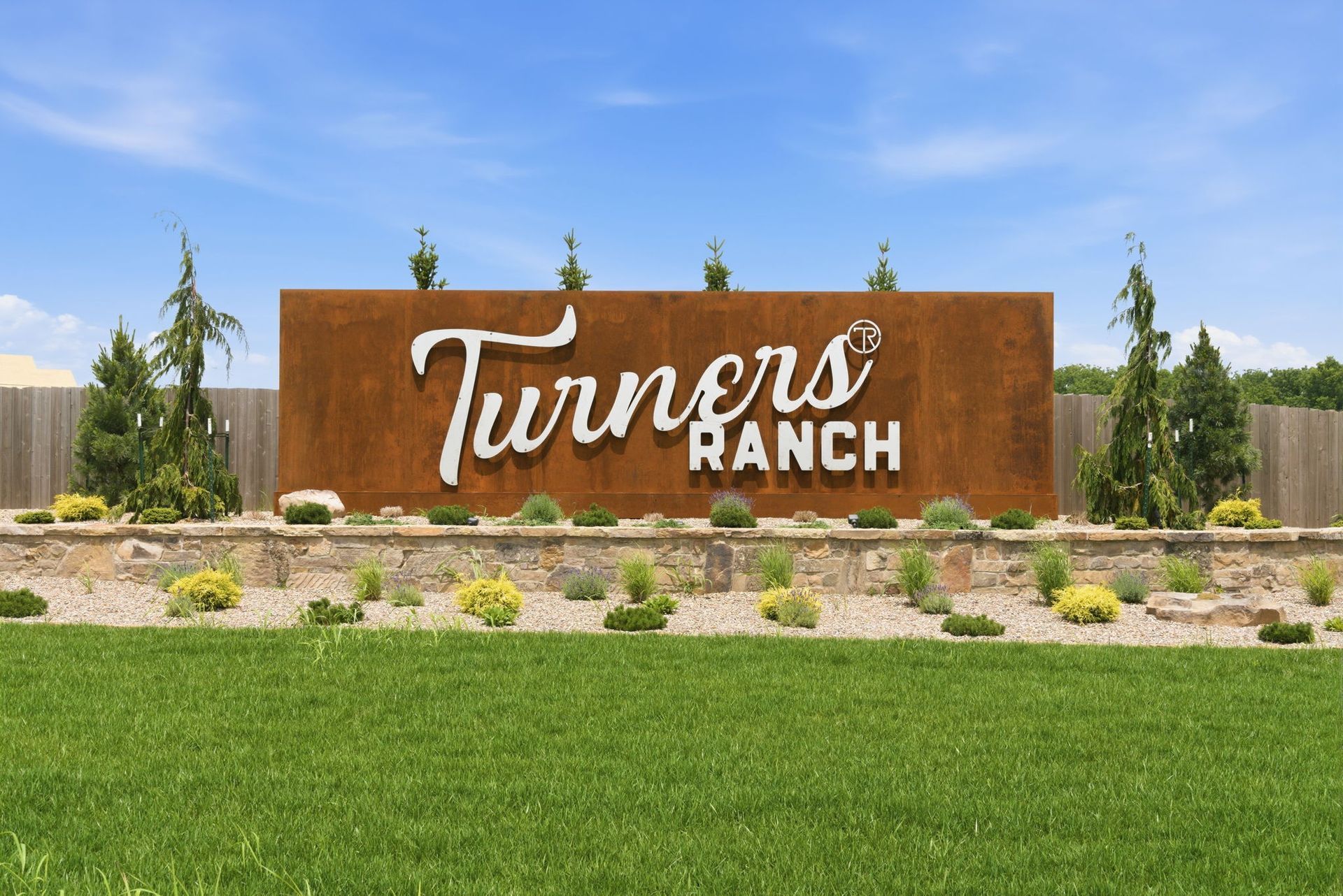 Turners Ranch sign in a landscaped roadside entrance with open fields in the background