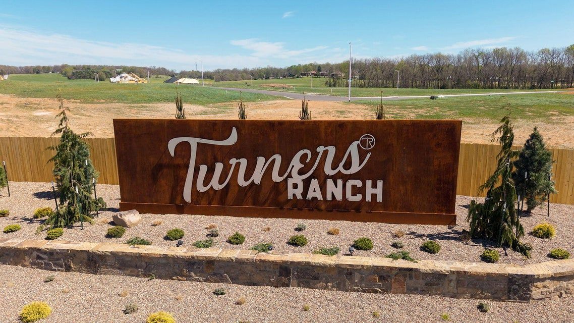 Brown sign with words and fresh landscaping with rock wall and blue skies