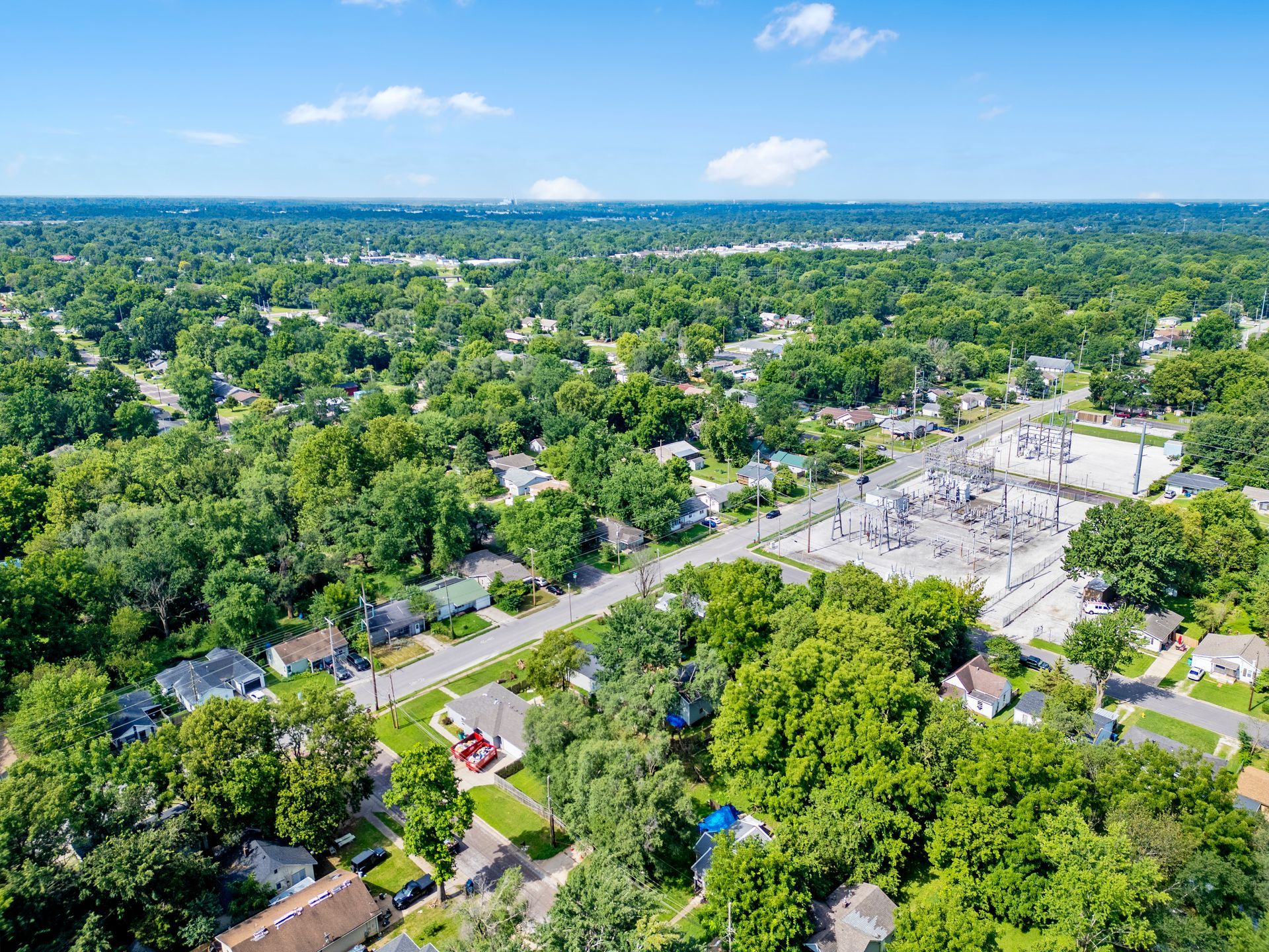 Aerial view of a green suburban neighborhood with a large paved sports court and tree-lined streets