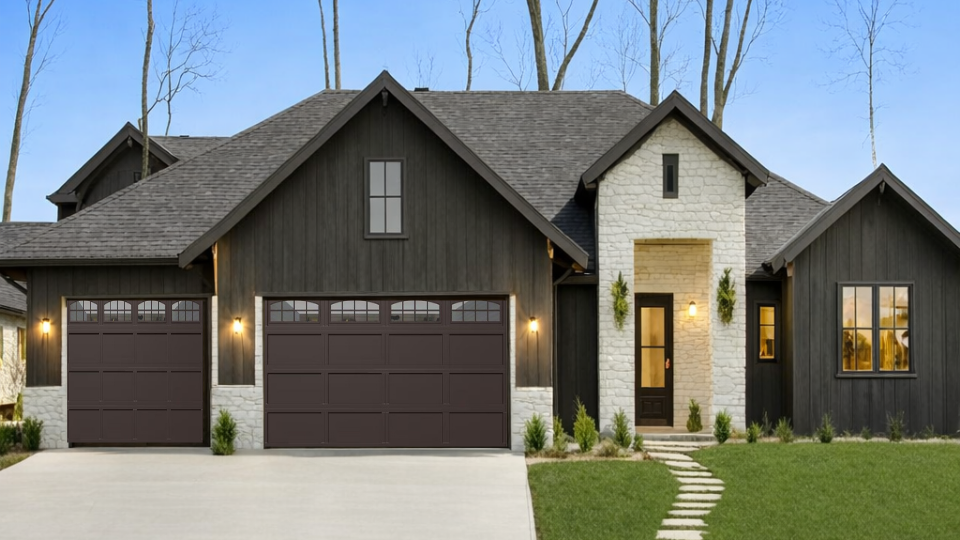 Modern two-story suburban house with brick facade, black garage doors, and a sloped driveway
