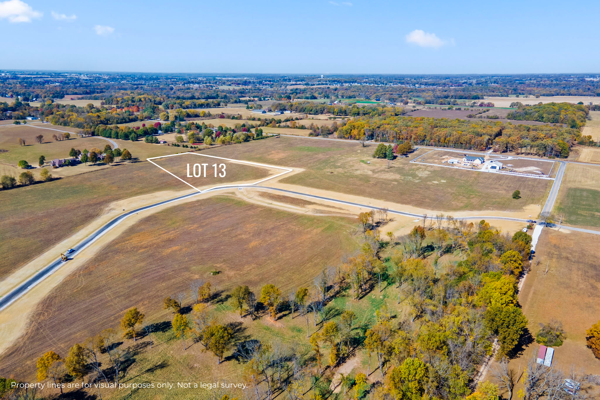 Aerial view of a suburban construction site beside open fields under a blue sky