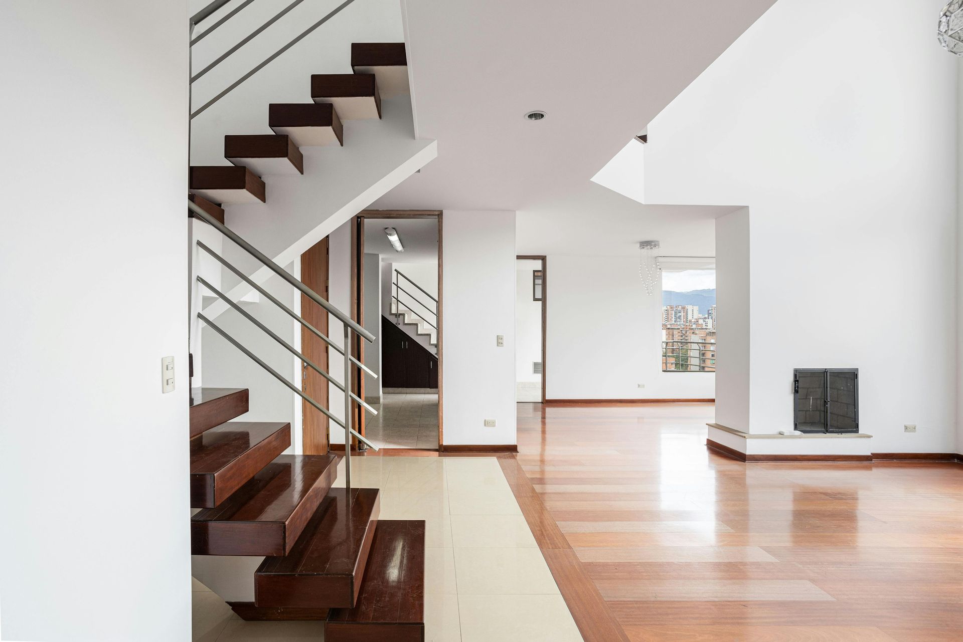 Modern living room with wooden staircase, hardwood floors, and fireplace