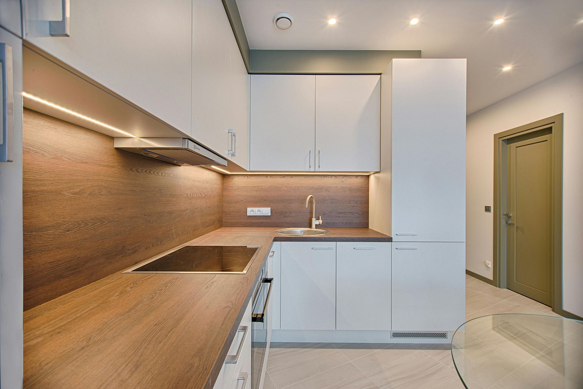 Modern minimalist kitchen with white cabinets, wood backsplash, and built-in appliances