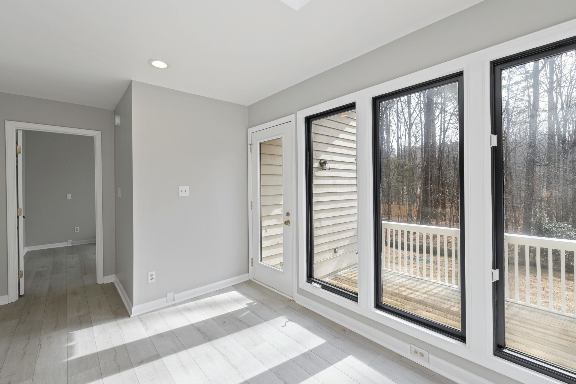 Bright empty room with gray walls, white floors, and large floor-to-ceiling windows.