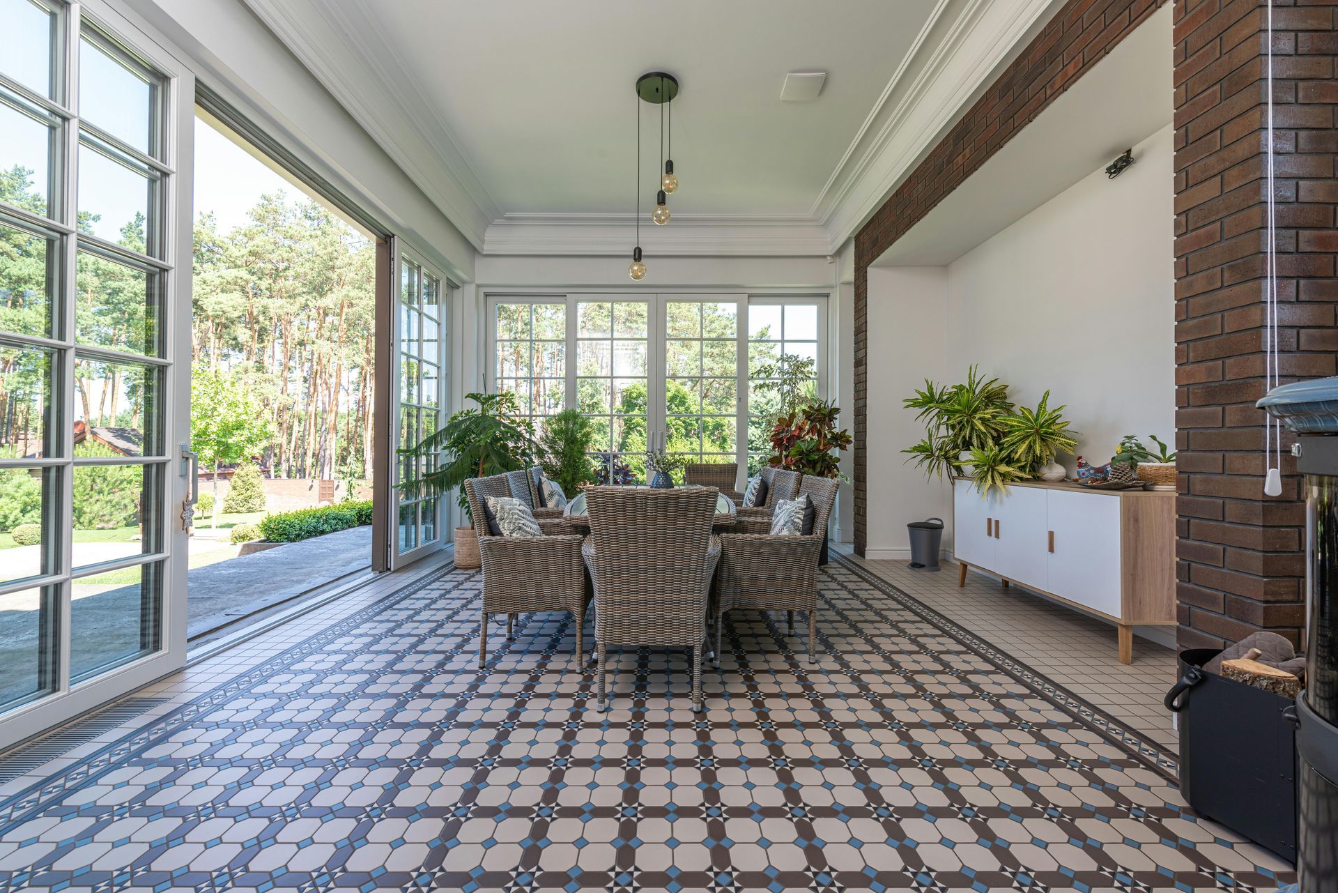 Covered patio with patterned tile floor, dining table, and wicker chairs opening to a garden.