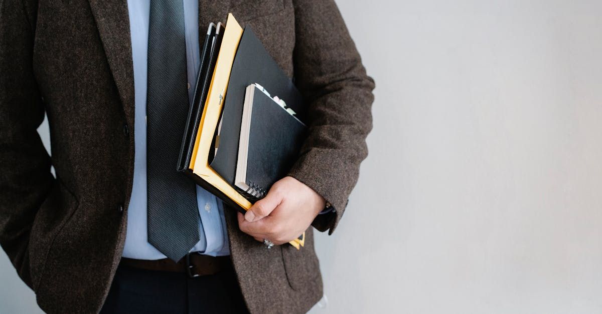 A man in a suit and tie is holding a stack of books.