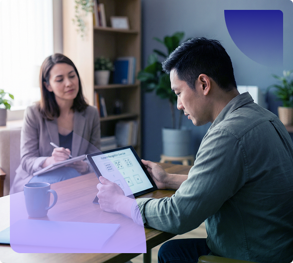 Two people discussing a tablet at a table in a bright office