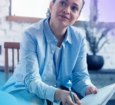 Woman in a blue shirt taking notes in a bright office setting