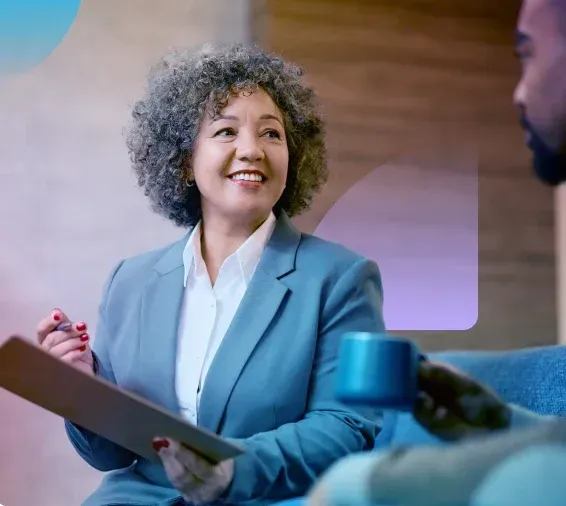 A clinician with a tablet smiling while talking with a patient