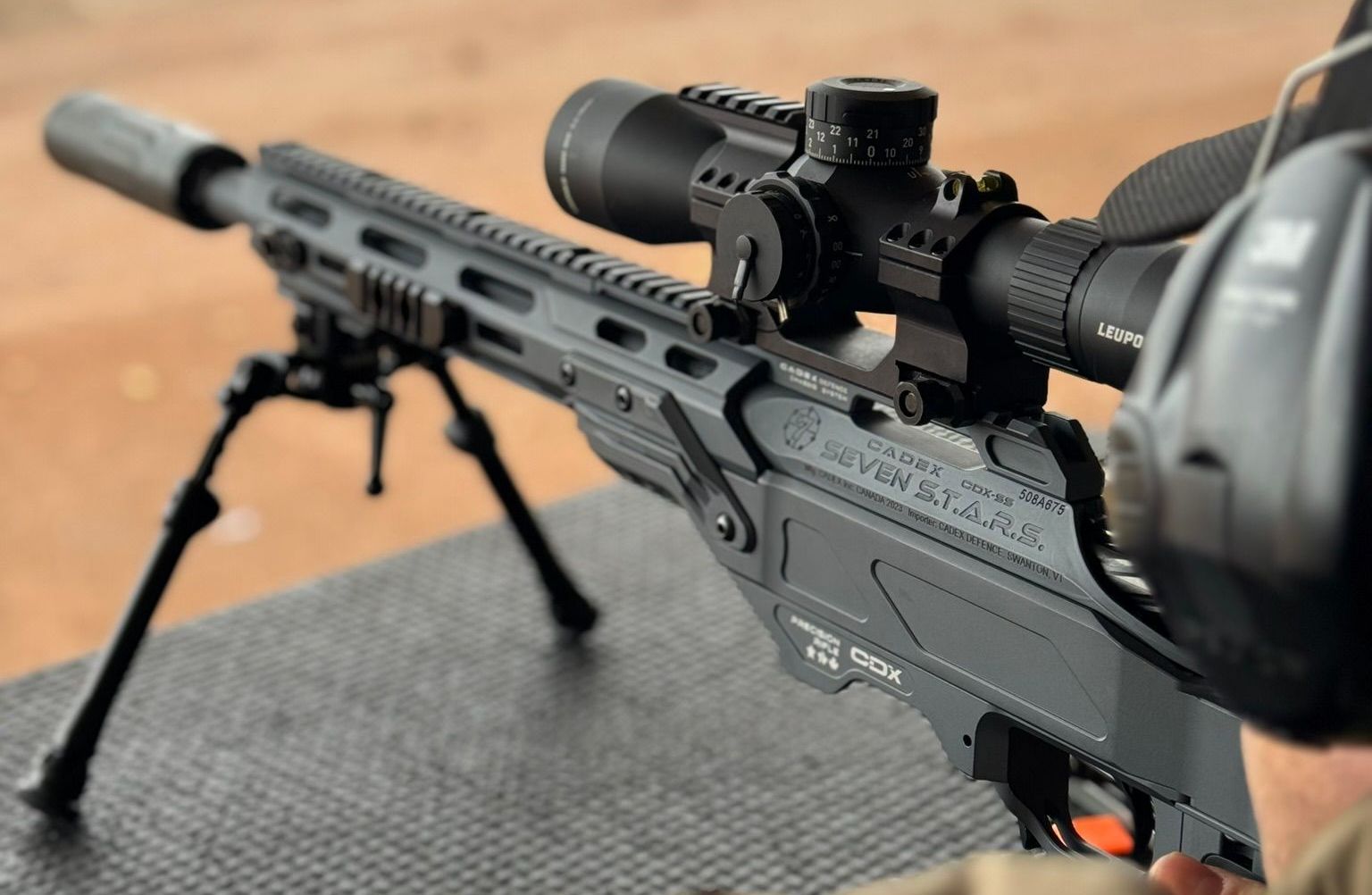 Graues Gewehr mit Zielfernrohr und Zweibein auf einem Schießstand.