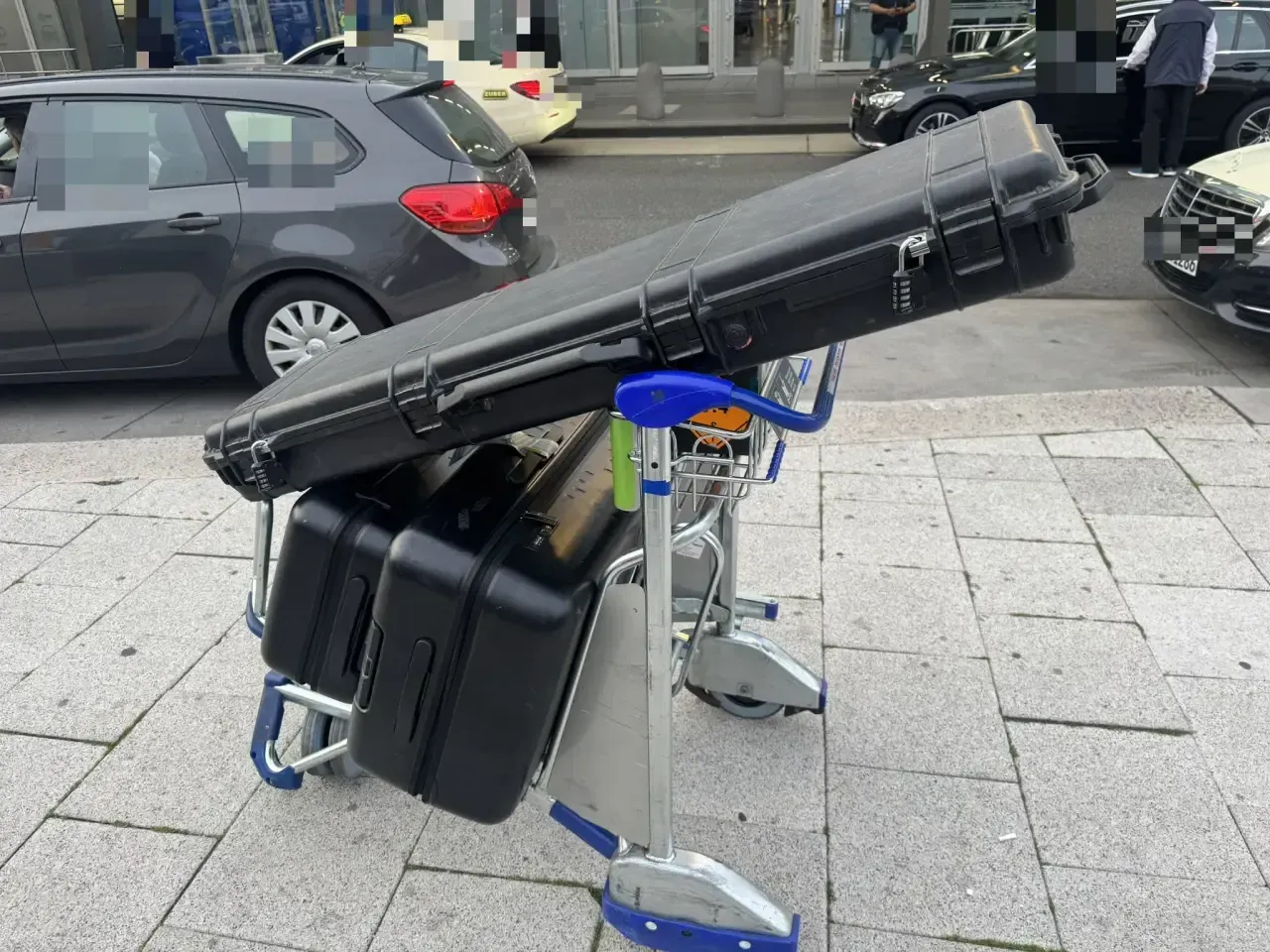 Gepäckwagen mit Waffenkoffer und Hartschalenkoffern vor dem Terminal – Anreise zum Flug mit Waffen