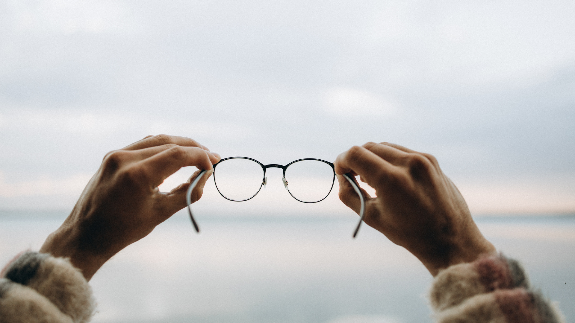 A person is holding a pair of glasses in their hands.