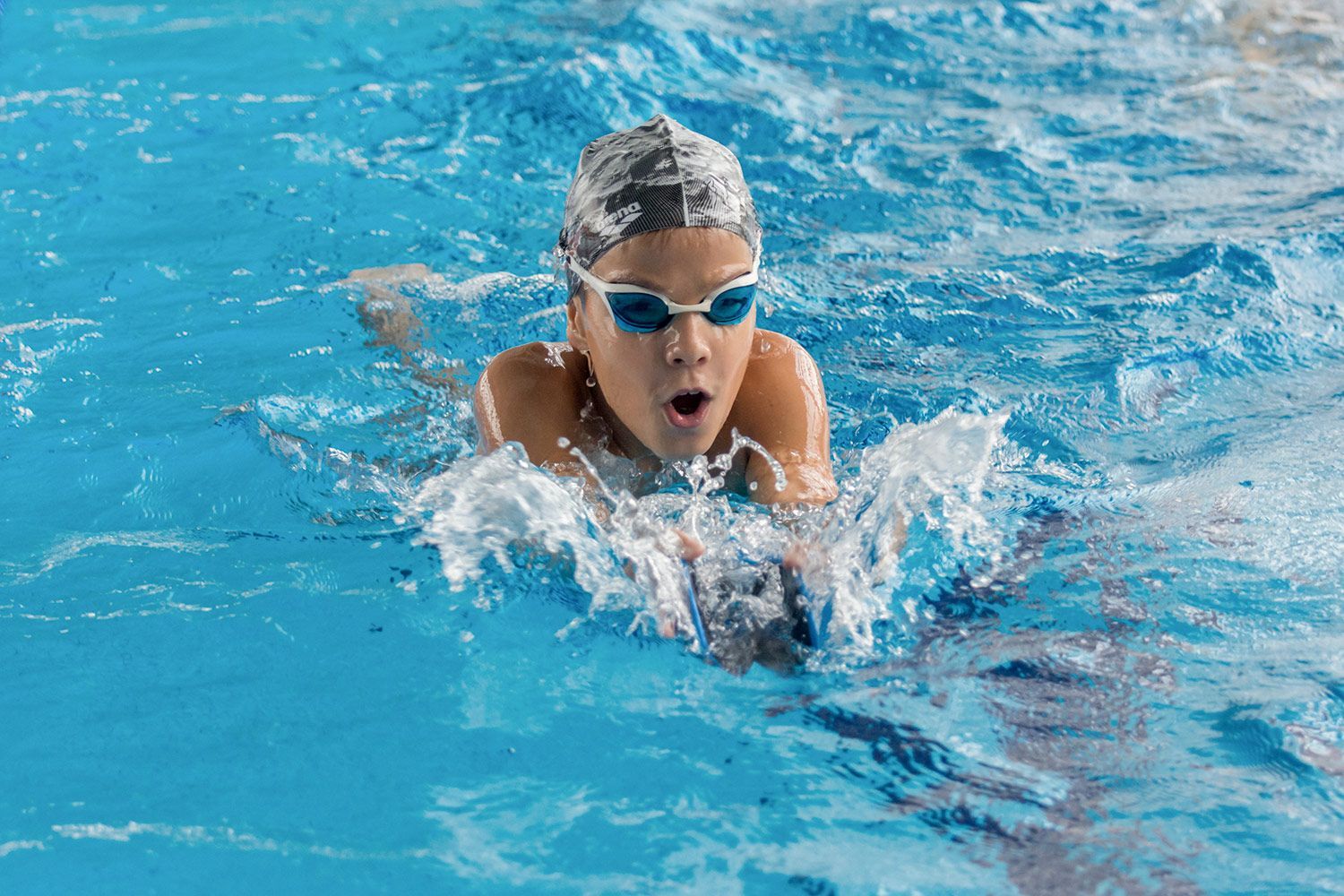 A young girl is swimming in a swimming pool.