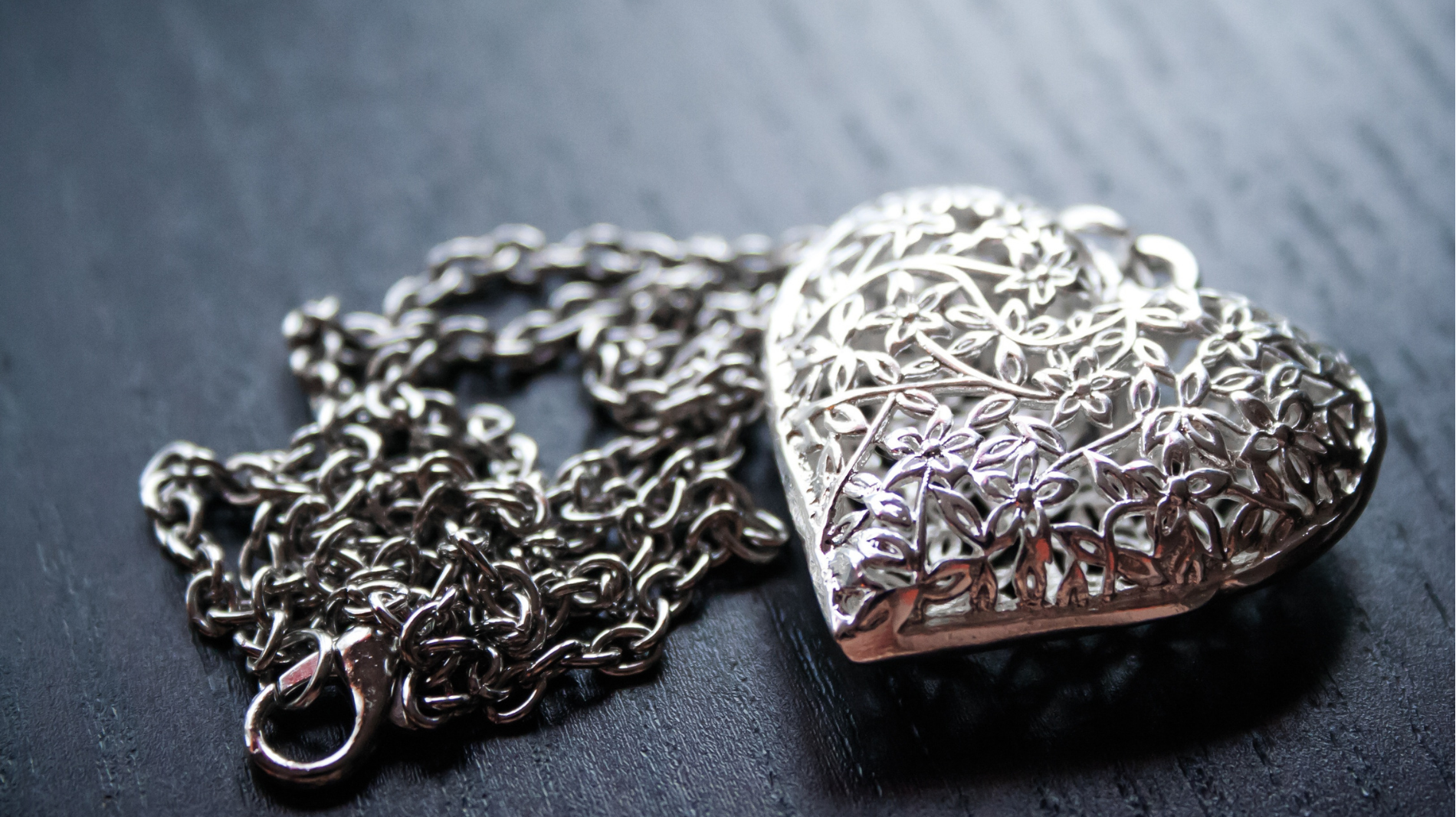 Silver heart-shaped pendant necklace on a dark surface