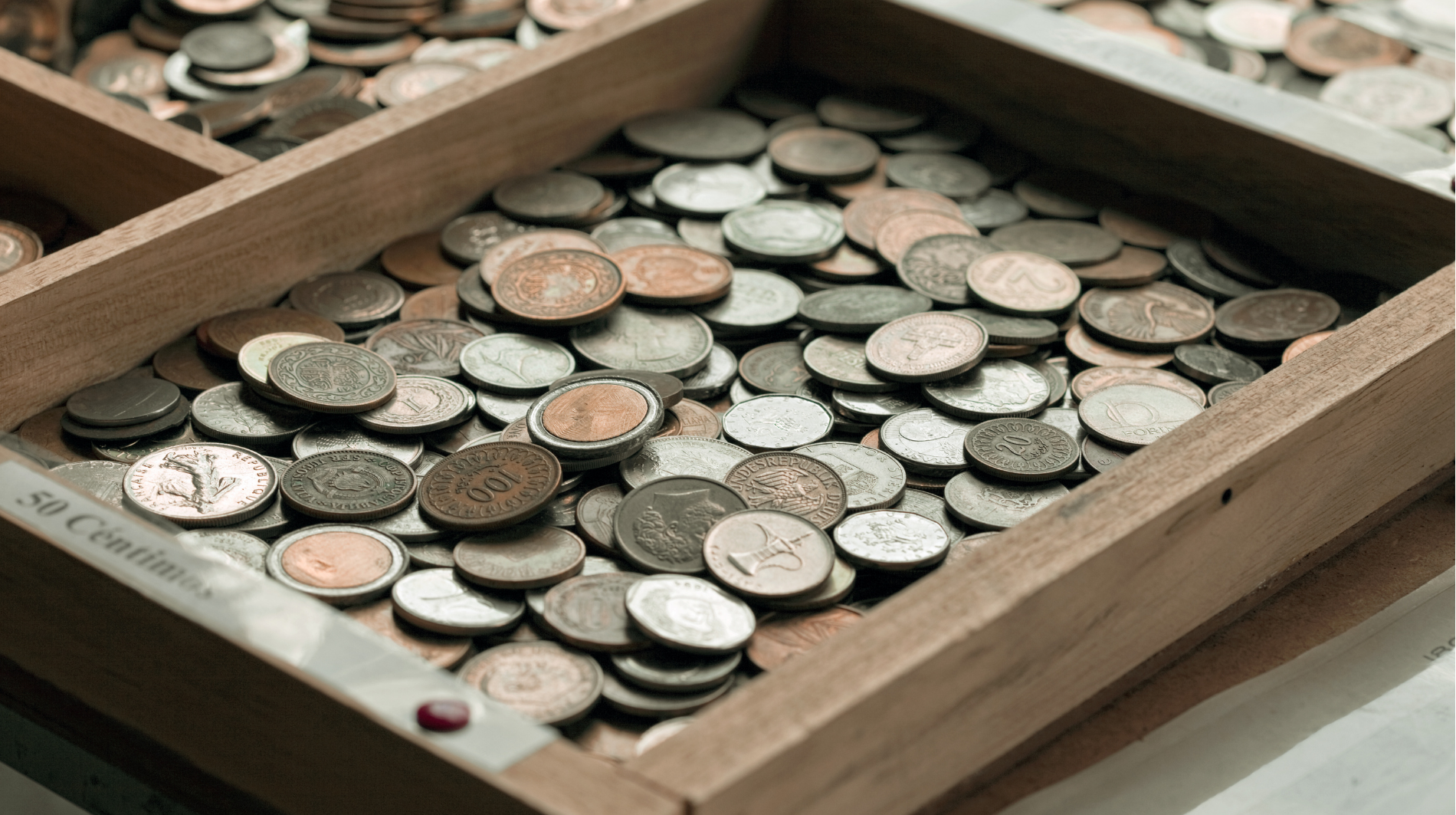Wooden tray filled with assorted coins, mostly silver and copper.