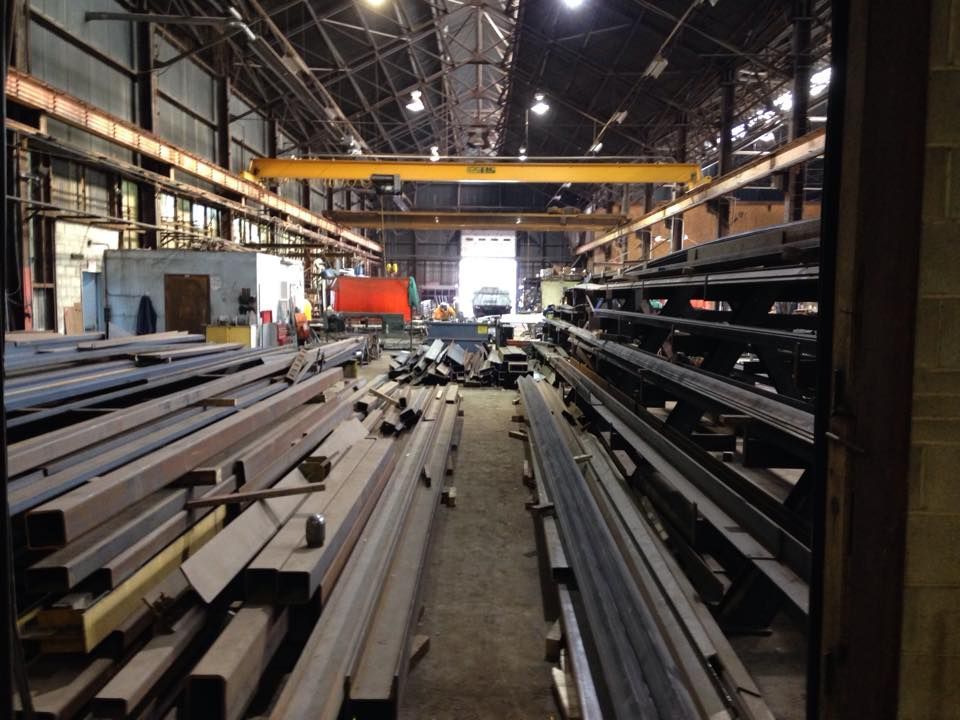A Bunch Of Metal Pipes Are Stacked On Top Of Each Other In A Warehouse — Albertson, NY — Patsy Strocchia & Sons Ir A Bunch Of Metal Pipes Are Stacked On Top Of Each Other In A Warehouse — Albertson, NY — Patsy Strocchia & Sons Ir