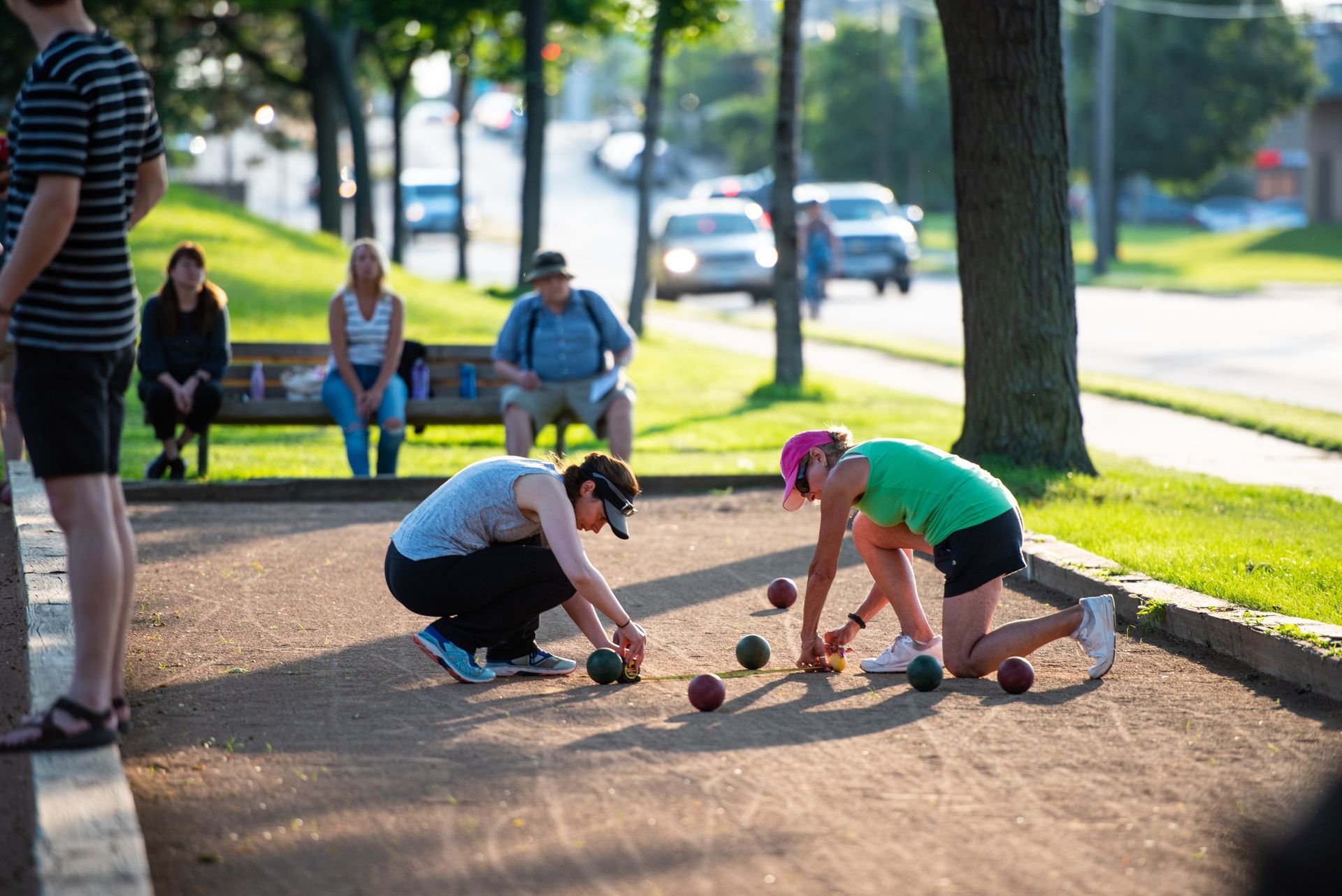Two people playing pickleball on an outdoor court, one in a blue shirt lunging for the ball.