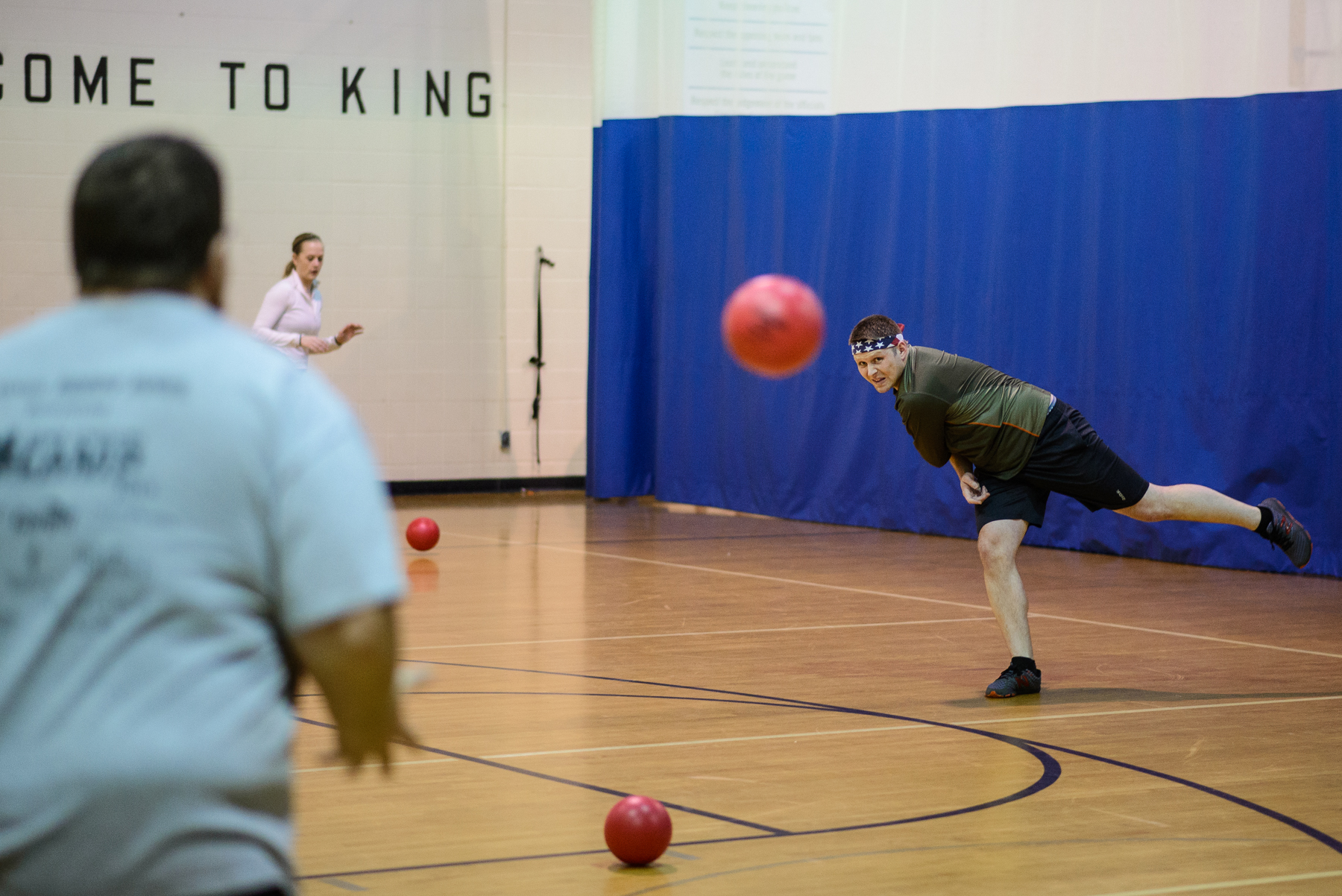 Basketball player holding ball, defended by a player with raised arms in indoor court setting.