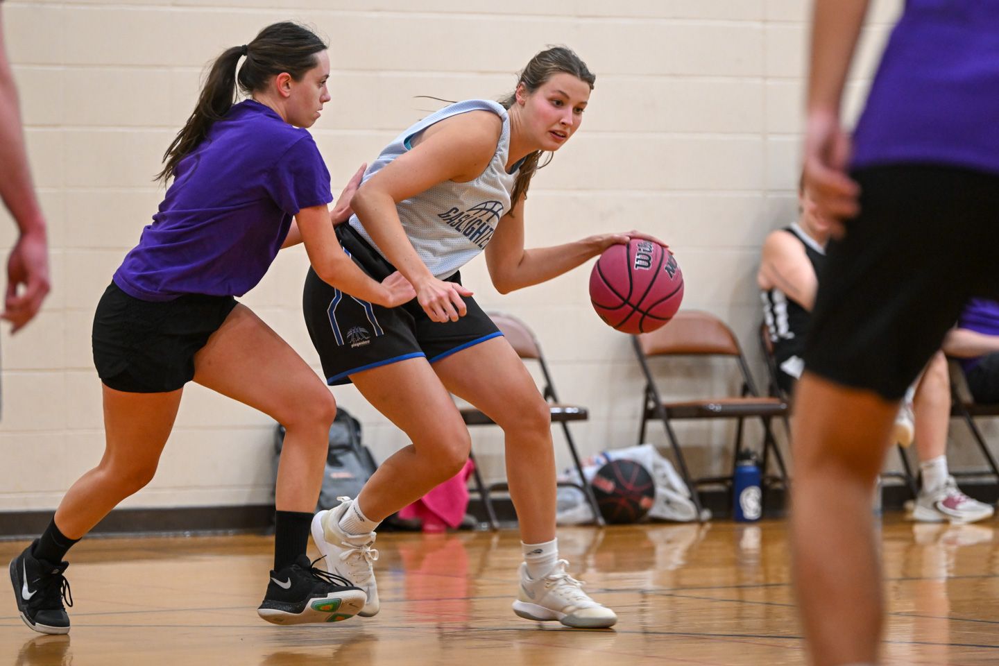 Basketball game: Referee handing ball to smiling player as opponent looks on.
