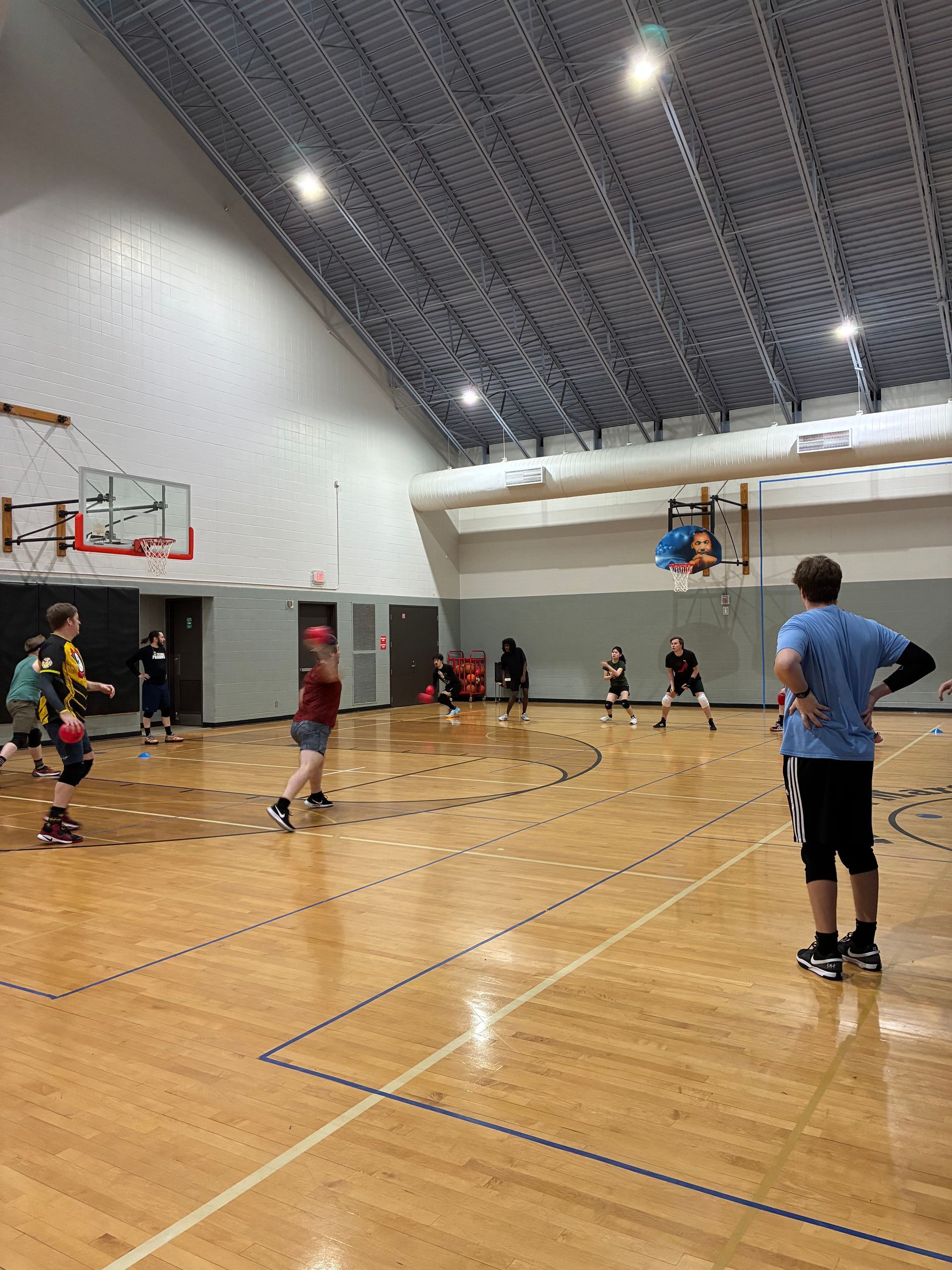 Basketball players in red jerseys huddle, smiling and strategizing in a gym.