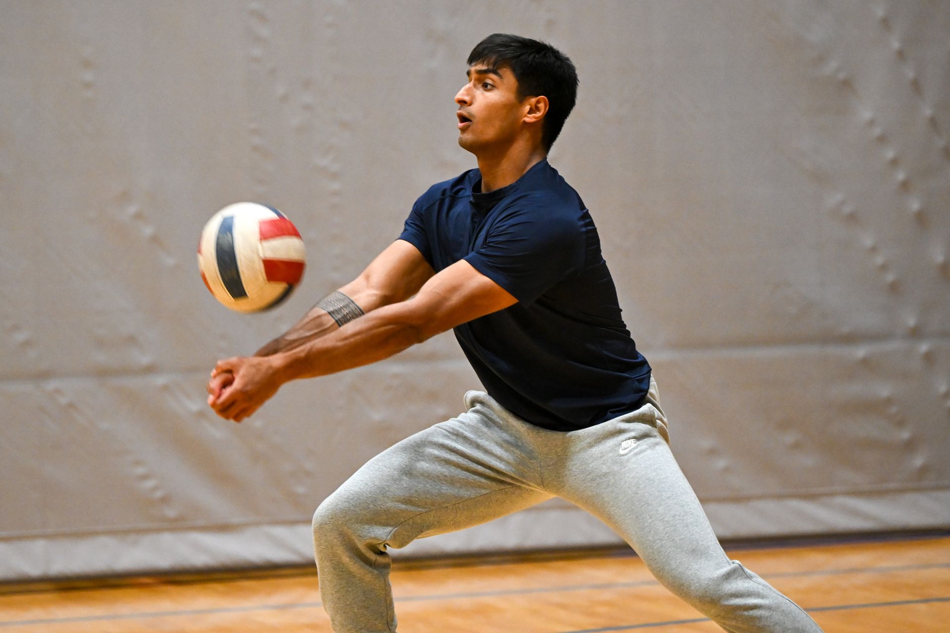 Basketball player in blue jersey dribbling, guarded by a player in orange. Gym setting.
