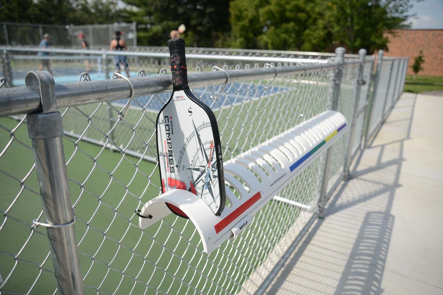 Man in blue shirt playing pickleball on a blue court near a white fence
