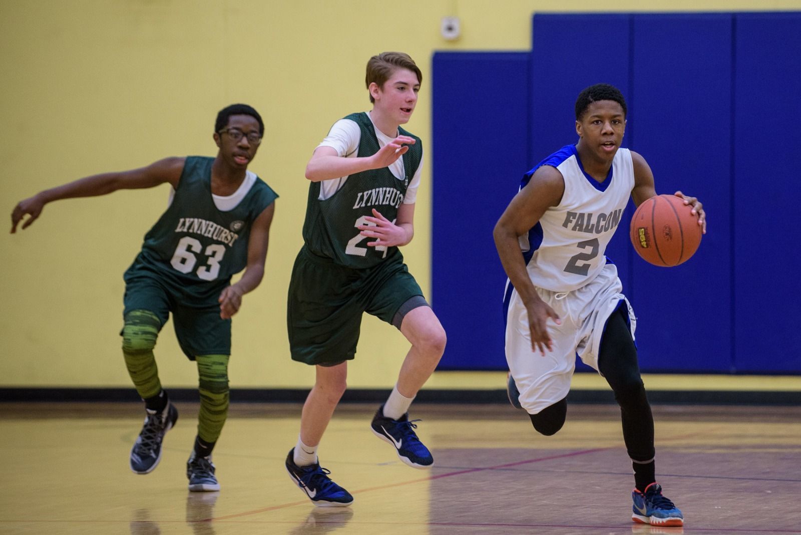 Basketball game: Referee handing ball to smiling player as opponent looks on.