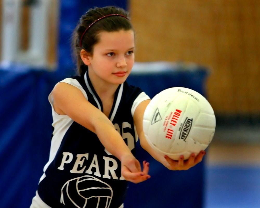 Basketball player holding ball, defended by a player with raised arms in indoor court setting.