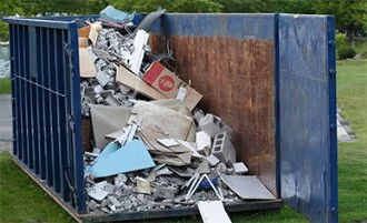 Overflowing blue dumpster filled with mixed construction debris and scrap wood outdoors