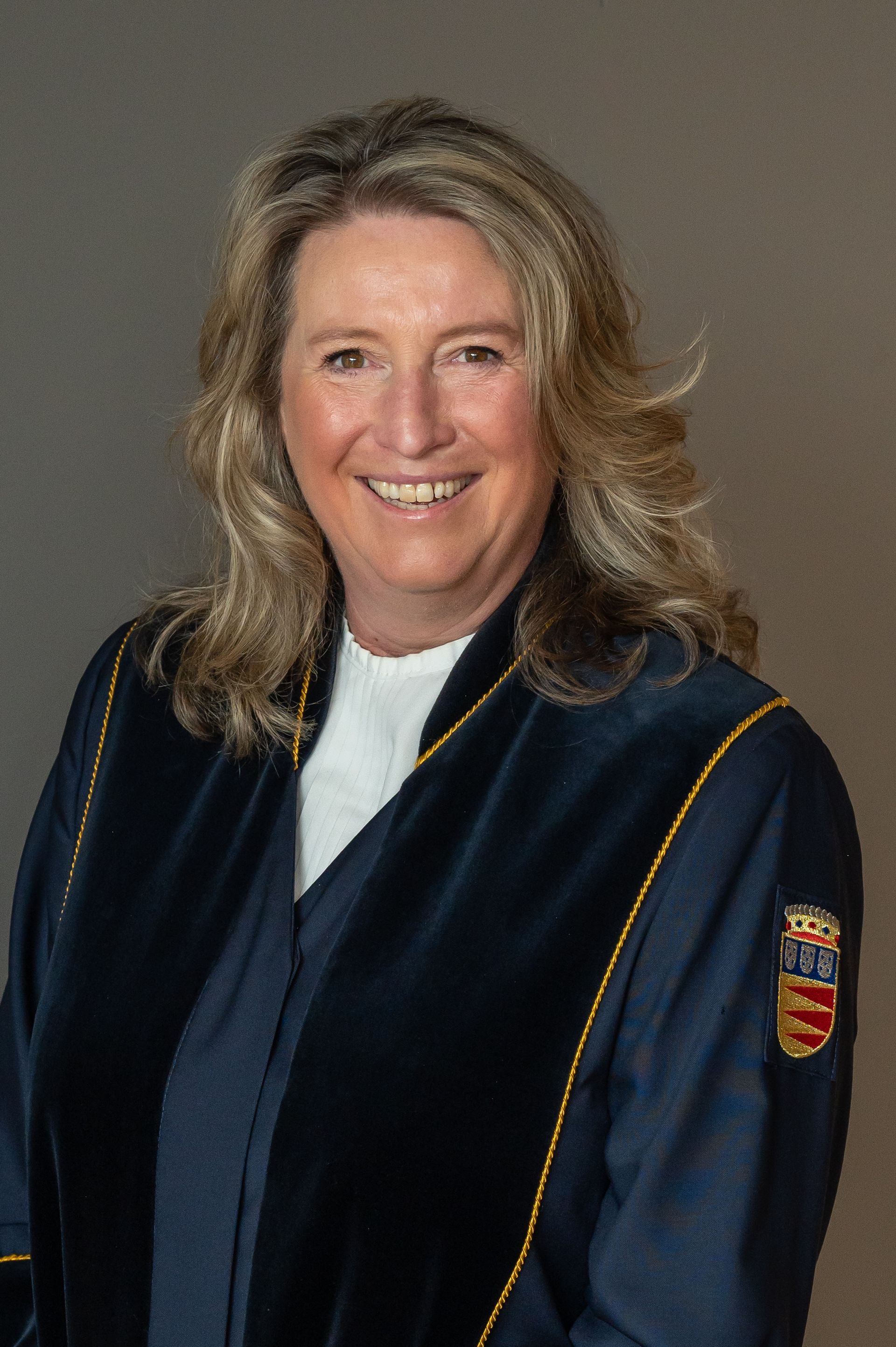 Portret van Marijke, trouwambtenaar en ceremoniespreker, met een warme en vriendelijke uitstraling.