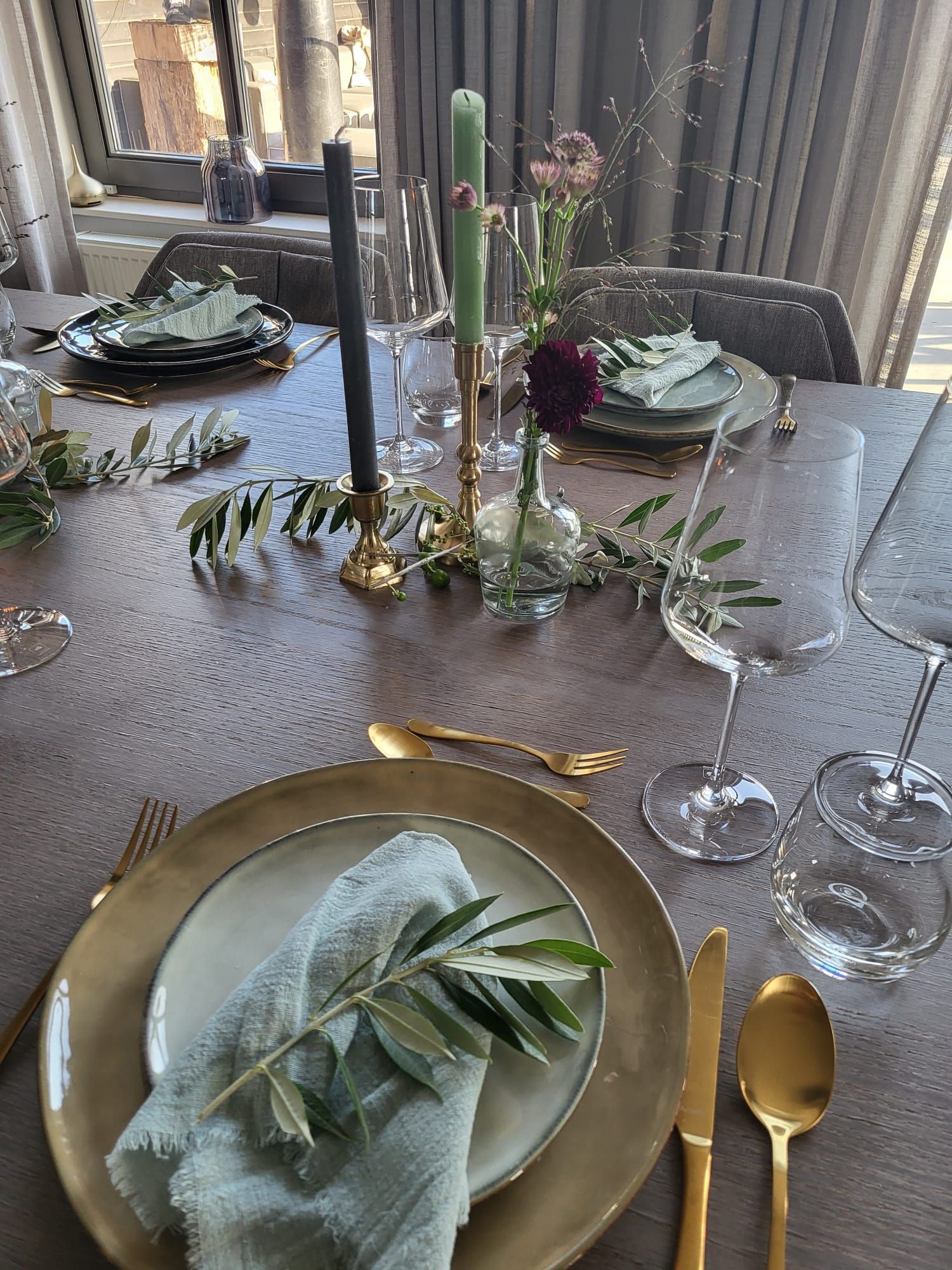 Stijlvol gedekte eettafel met kaarsen, bloemen en groen, voorbereid voor een intieme huwelijksviering.