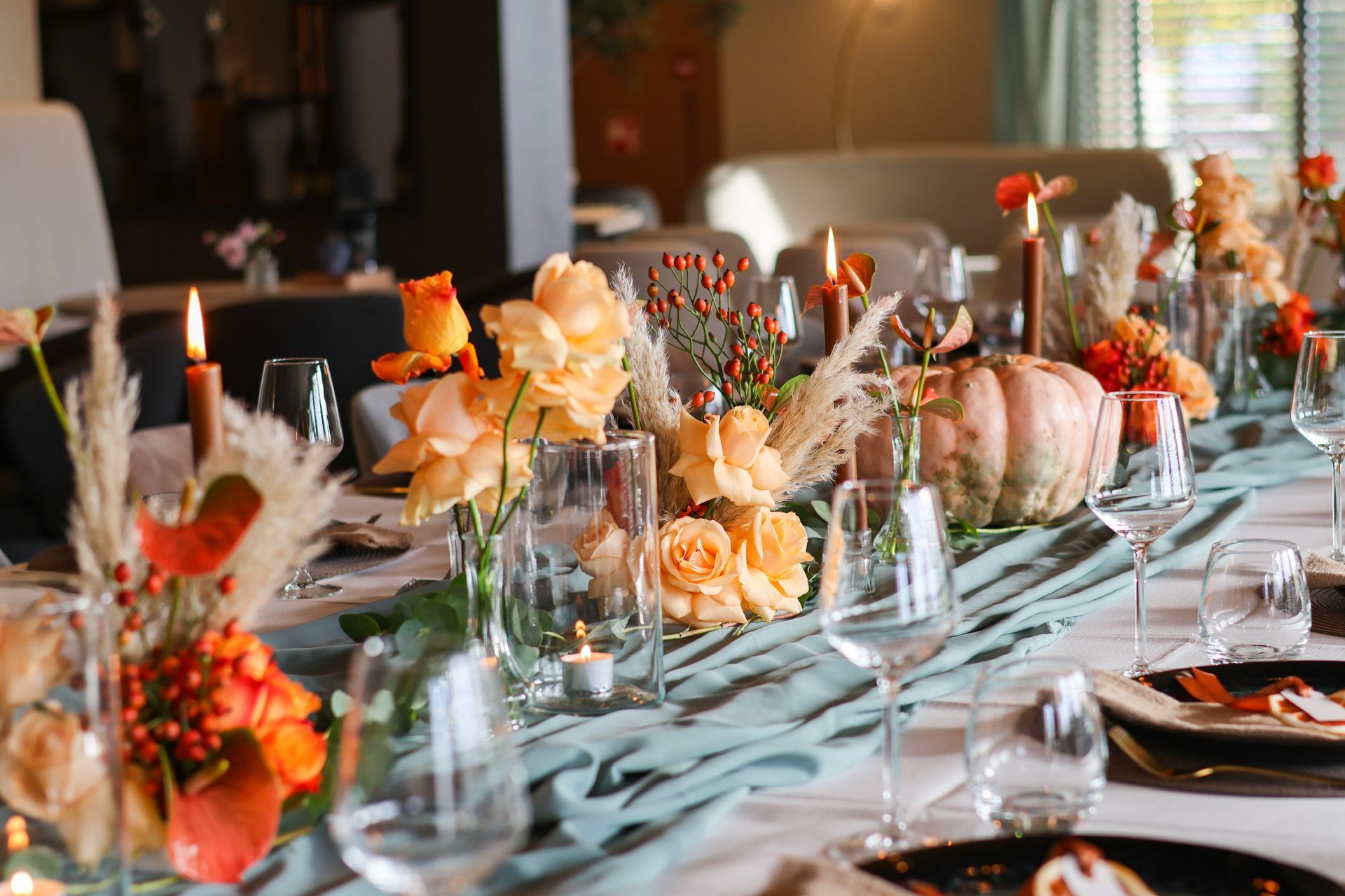 Romantisch gedekte tafel met bloemen, kaarsen en natuurlijke details voor een warme en sfeervolle huwelijkssetting.