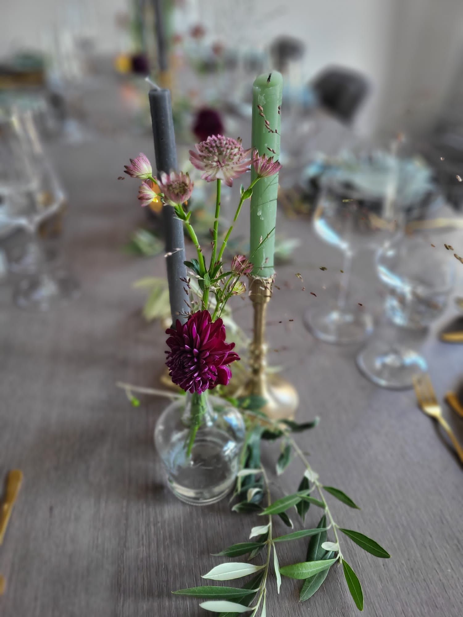 Sfeervolle tafeldecoratie met kaarsen en bloemen, passend bij een intieme en stijlvolle huwelijkssetting.