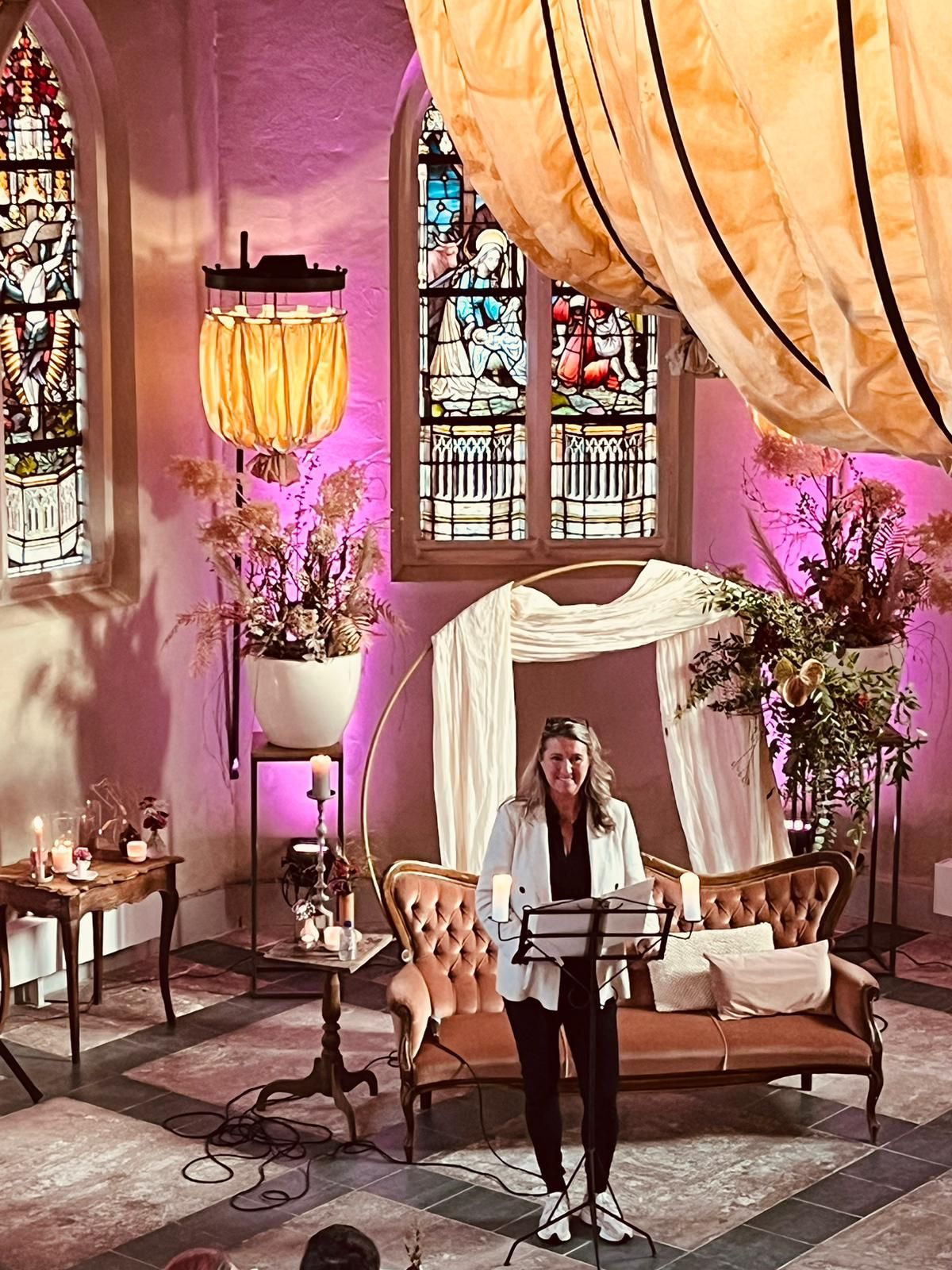 Sfeervolle kerkelijke trouwlocatie met glas-in-loodramen, zachte verlichting en romantische decoratie voor een intieme huwelijksceremonie.