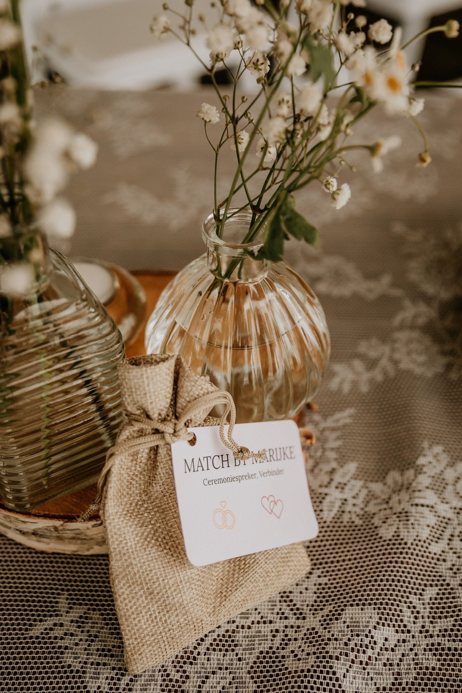 Fijn bloemstuk met kleine witte bloemetjes in een glazen vaasje, subtiel detail van een romantische huwelijkssetting.