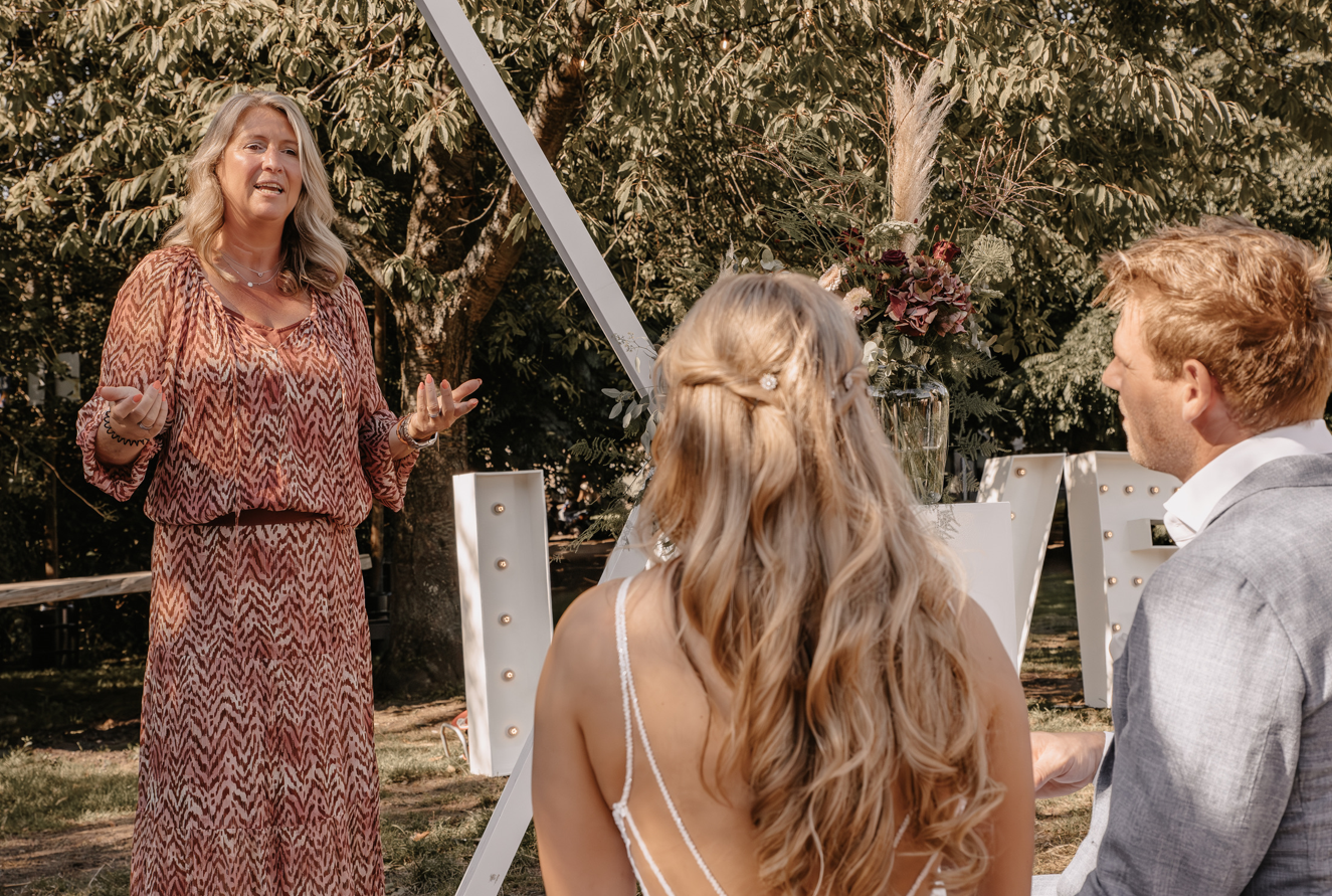 Ceremoniespreker Marijke spreekt het bruidspaar toe tijdens een persoonlijke buitenbruiloft, met warme woorden en oprechte betrokkenheid.