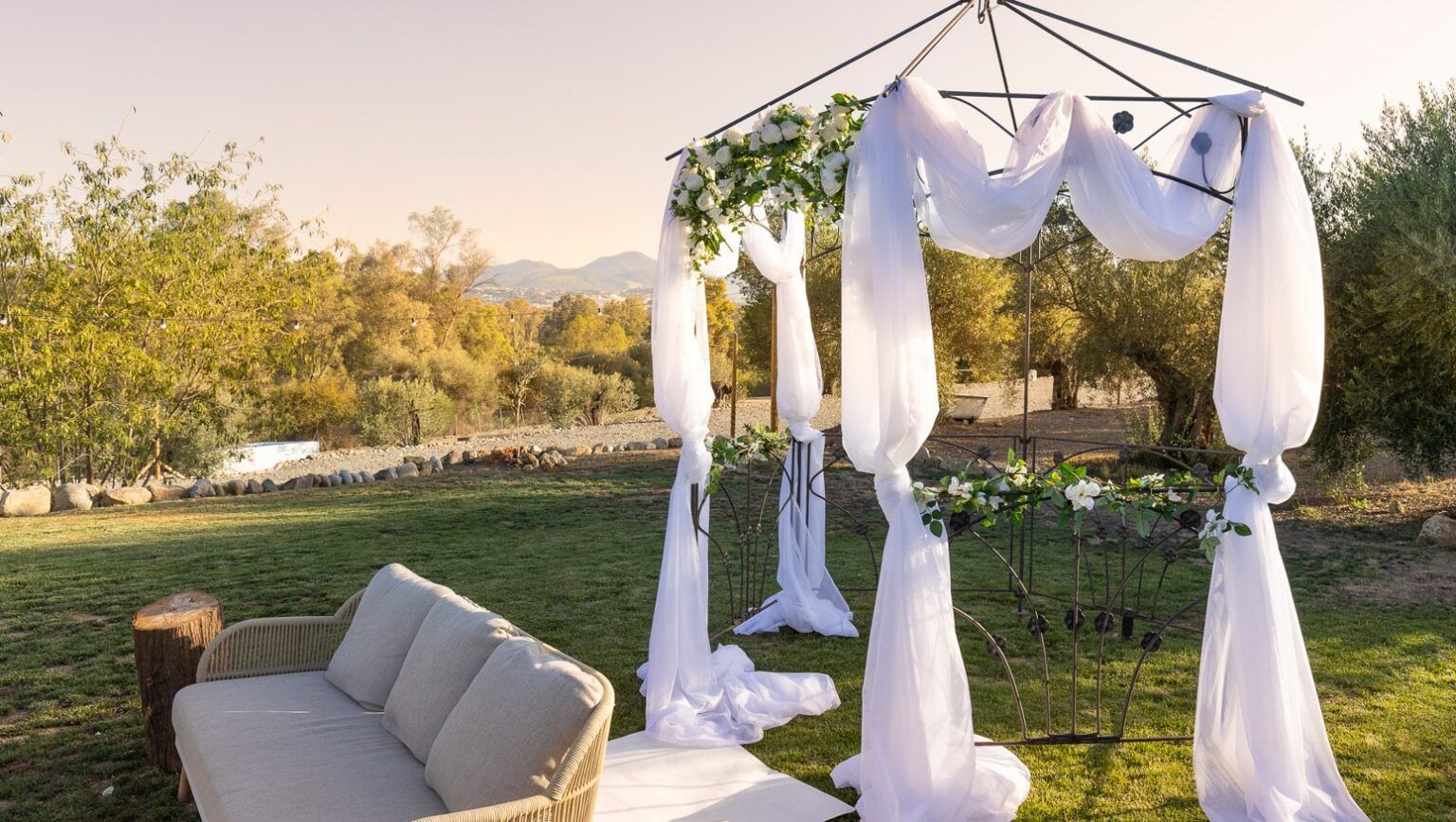 Romantische ceremonieplek in de buitenlucht met witte doeken en groen, perfect voor een intieme huwelijksceremonie in de natuur.