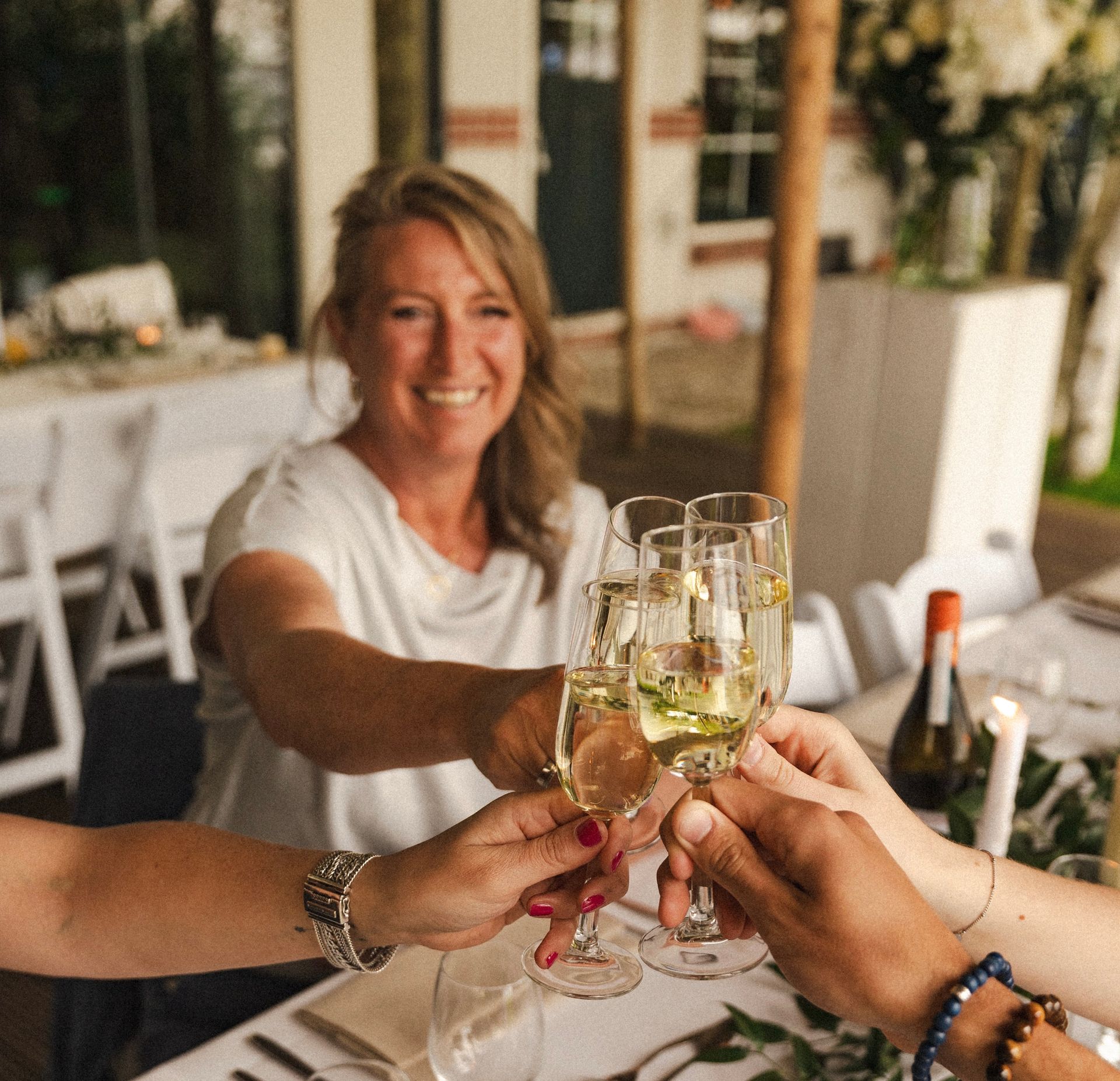 Marijke proost met champagne tijdens een ontspannen en feestelijk huwelijksmoment vol warmte en verbondenheid.