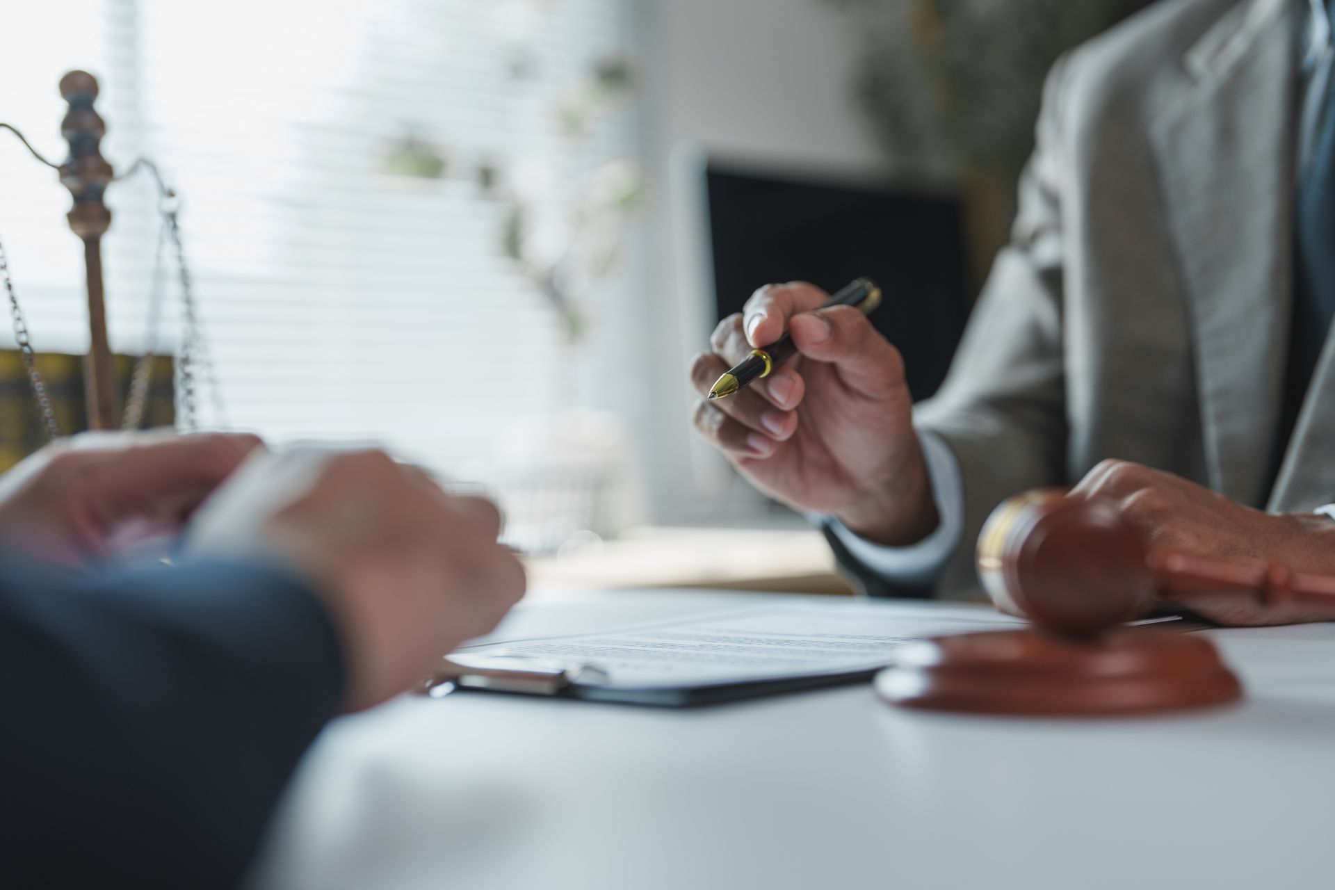 Client signing documents with a lawyer, gavel on desk in legal office.