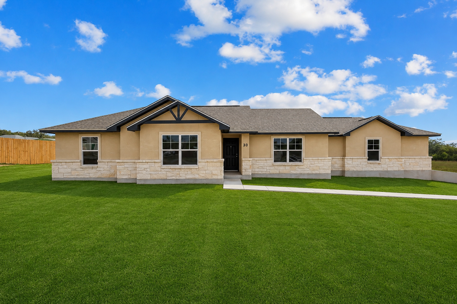 Single-story beige house with a large green lawn and blue sky with clouds