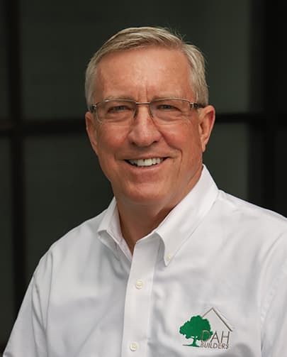Man in white shirt with glasses, smiling; logo with house and tree.