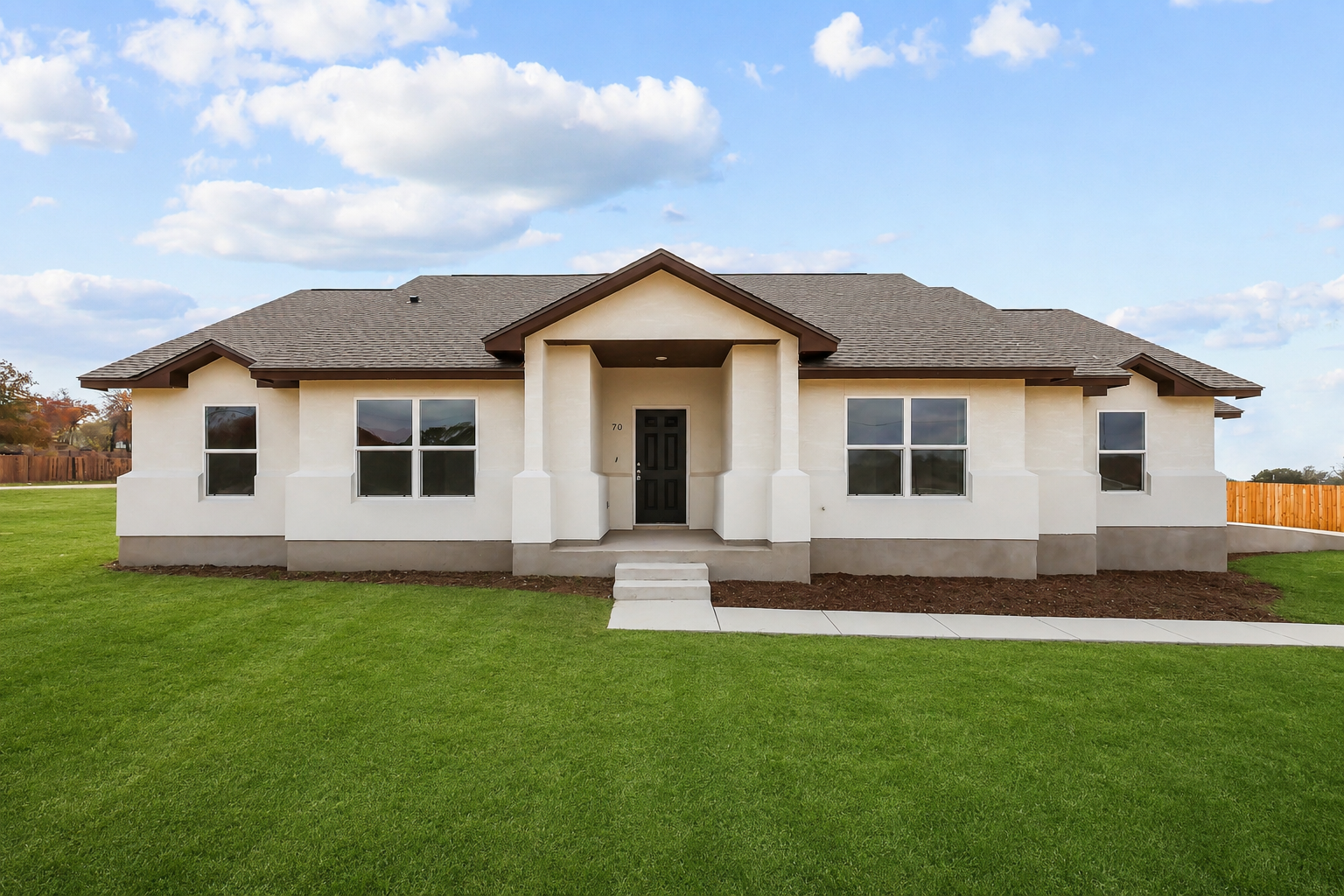 Single-story beige house with a tiled roof and a green lawn under a blue sky