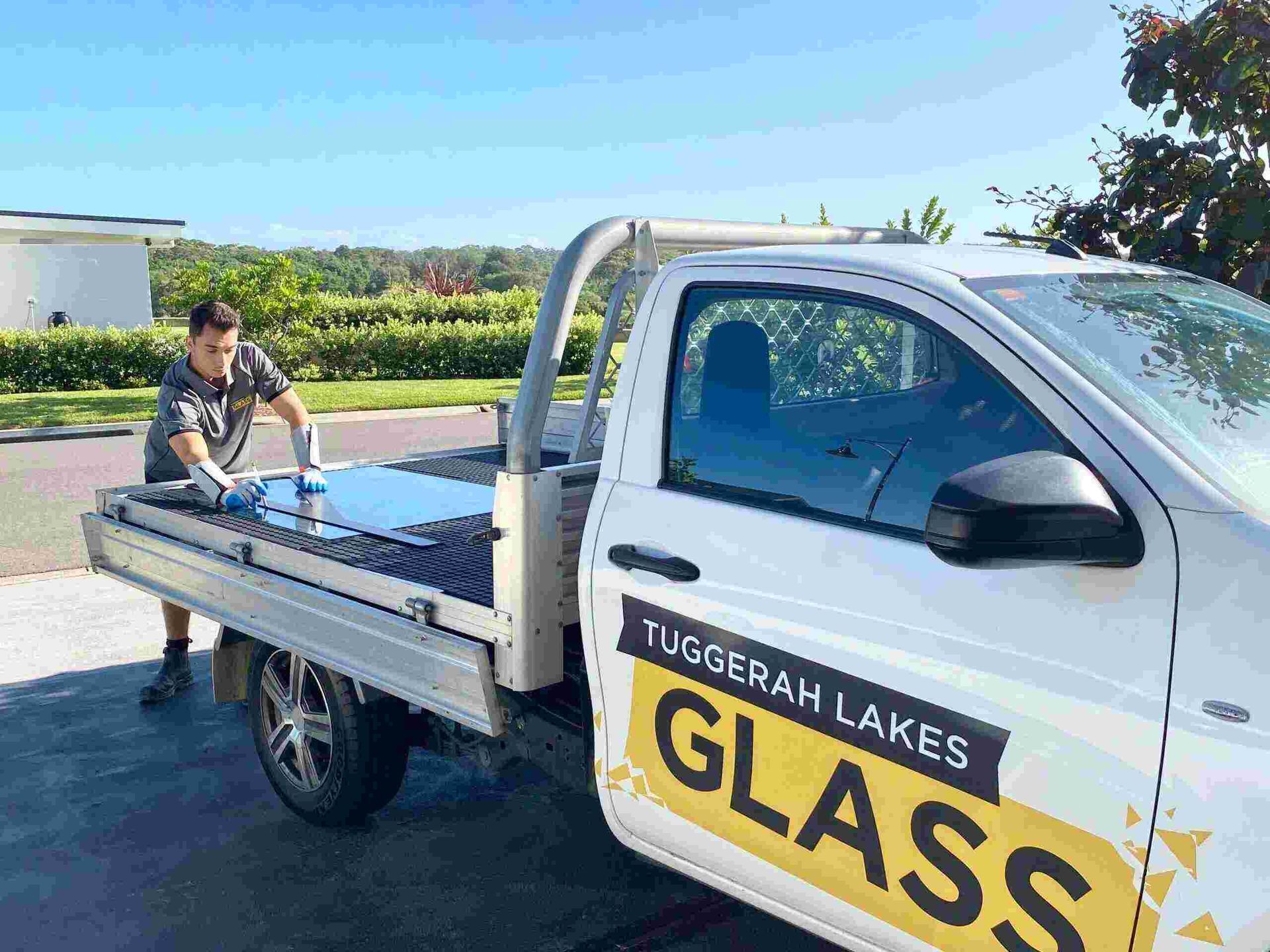 A man is loading a piece of glass into the back of a truck. — Tuggerah Lakes Glass In Tumbi Umbi, NSW