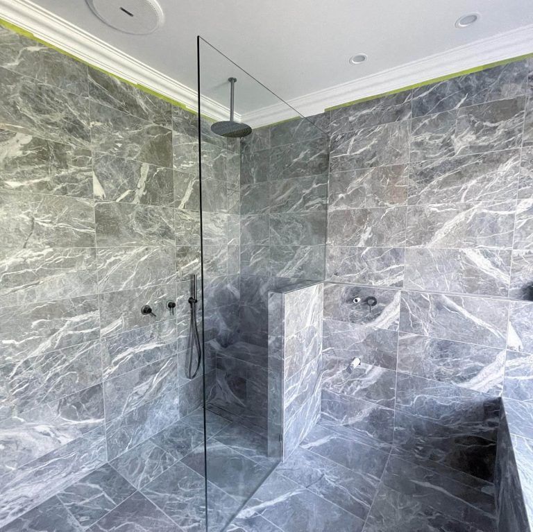 A bathroom with marble tiles and a walk in shower with a glass door. — Tuggerah Lakes Glass In Tumbi Umbi, NSW
