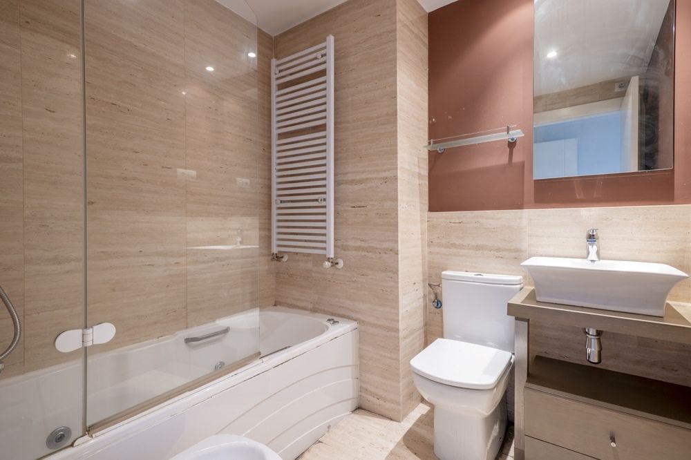 A bathroom with a bathtub , toilet , sink and mirror. — Tuggerah Lakes Glass In Tumbi Umbi, NSW