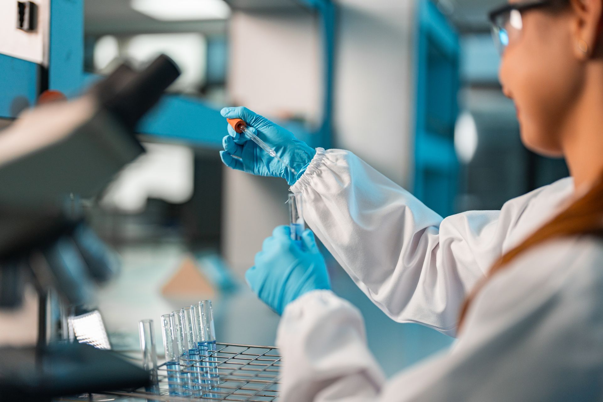 A female scientist is working in a laboratory holding a pipette.