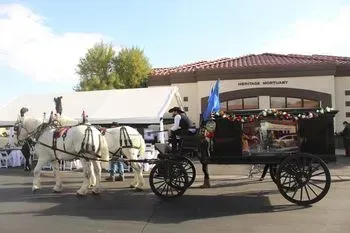 White horse-drawn carriage in front of a building with a tiled roof and event tents