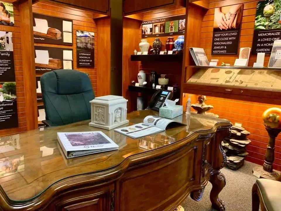 Wooden desk in a cozy office or study, with a green chair, papers, and warm amber lighting.