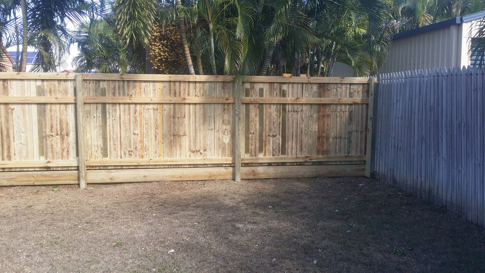 Wooden Backyard Fence With Gravel Ground, Palm Trees Behind It — Fencing Around in Garbutt, QLD